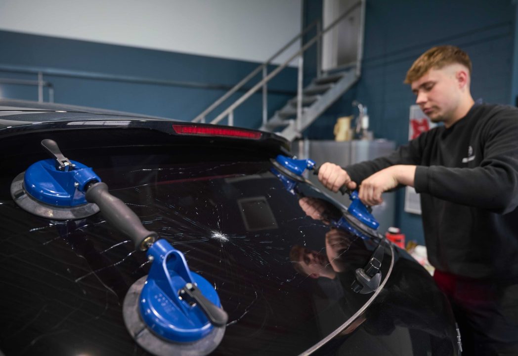 Mitarbeiter der Kfz-Meisterwerkstatt PROH in Mayen entfernt eine stark beschädigte Heckscheibe mit Spezialwerkzeug – professioneller Autoglas-Service inklusive Scheibentausch und Originalteilen.